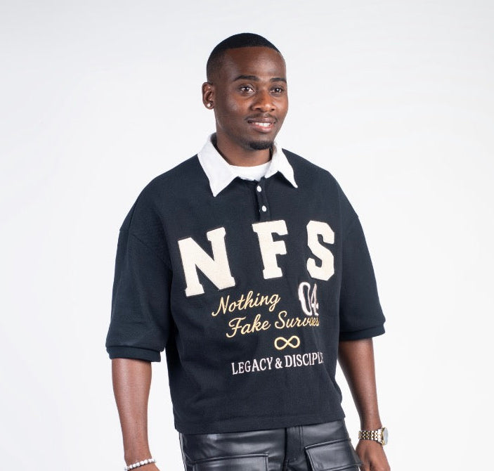 Man wearing a black polo shirt with 'NFS' text, black pants, and tan shoes on a white background