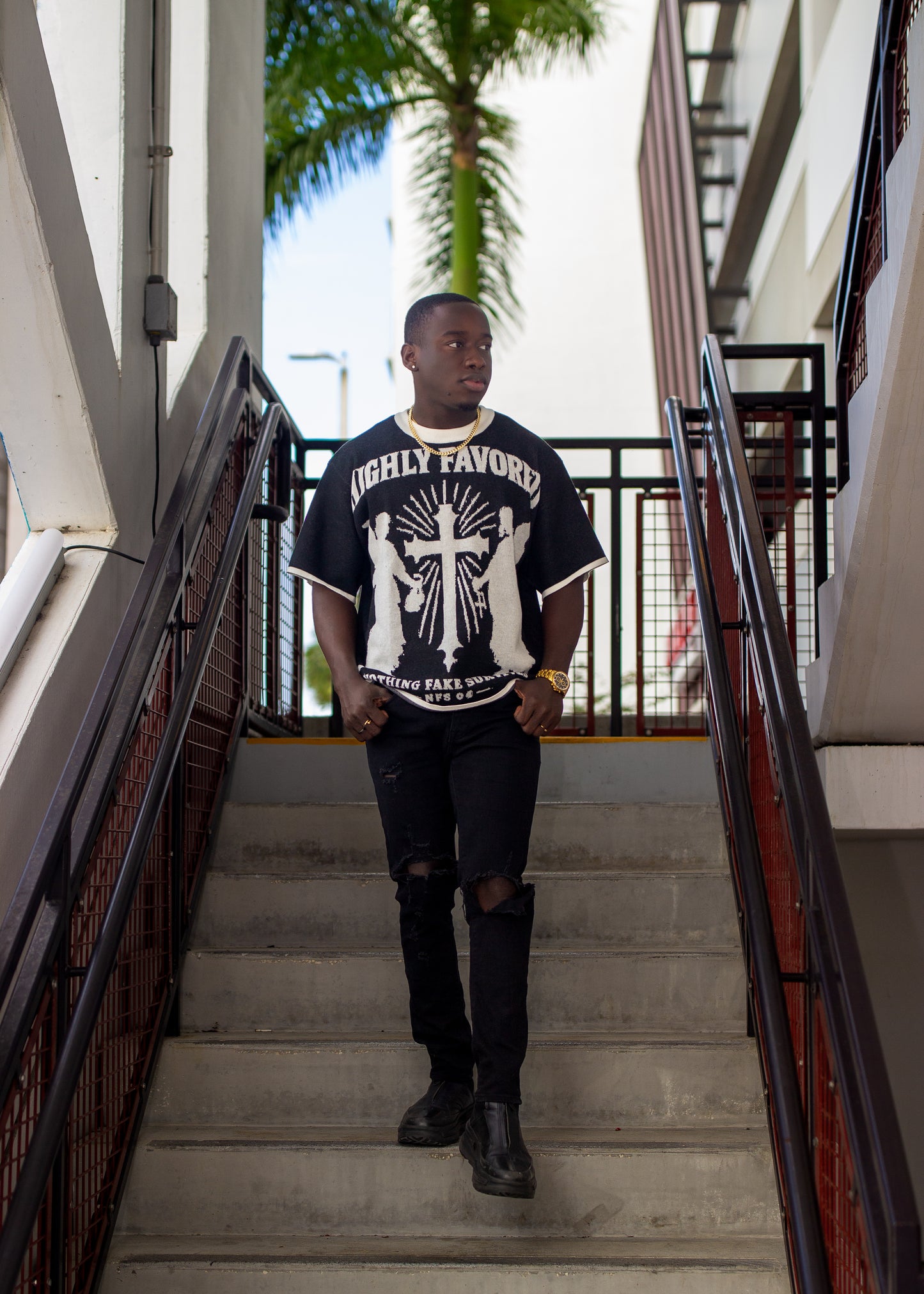 Person wearing a black t-shirt with white graphics on stairs