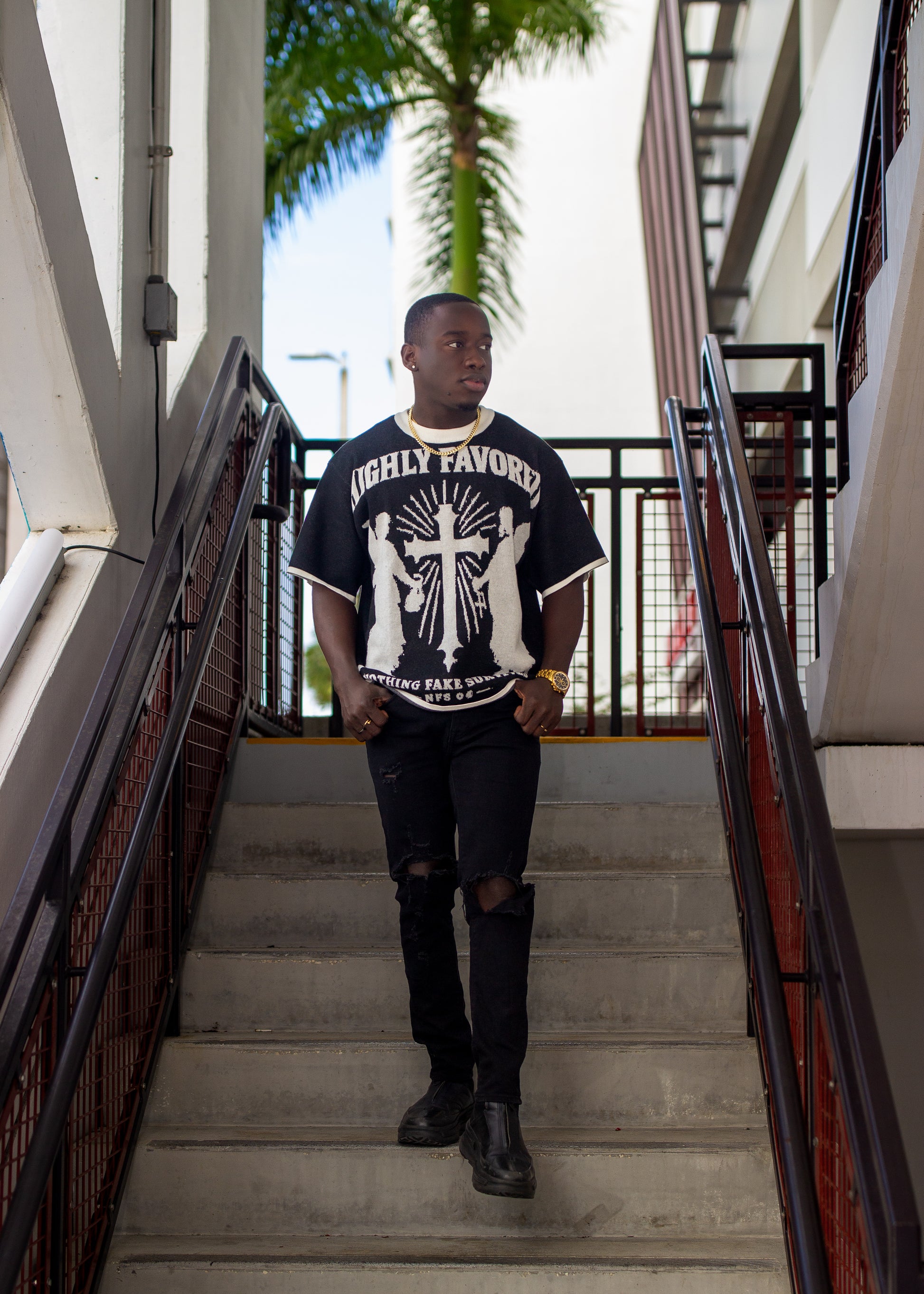 Person wearing a black t-shirt with white graphics on stairs