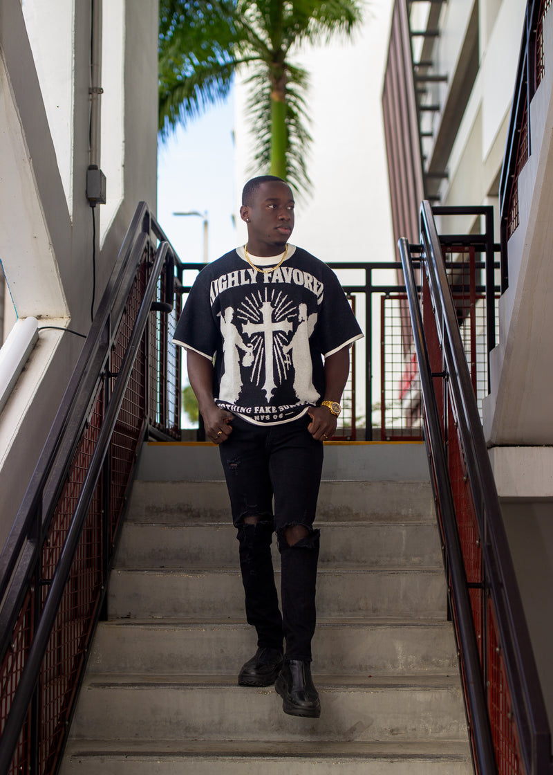 Person wearing a black t-shirt with white graphics on stairs