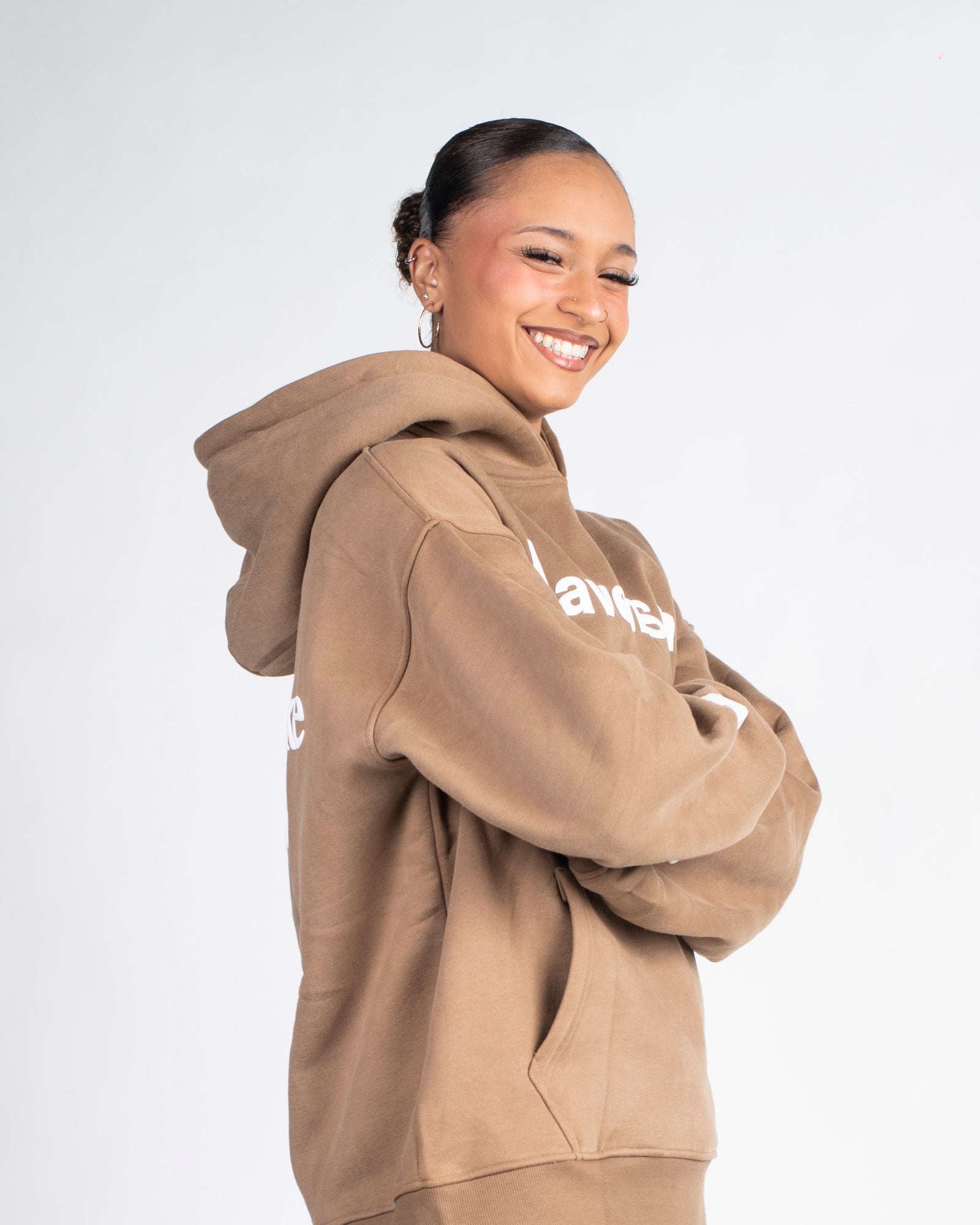 Woman wearing a beige NFS hoodie on a white background